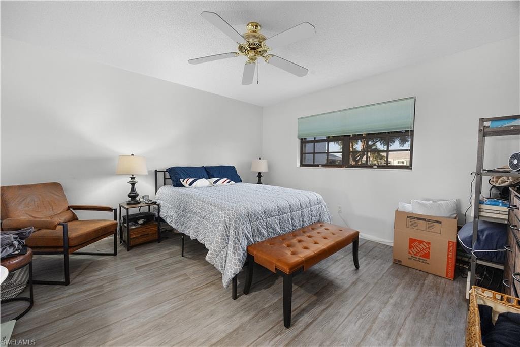 Bedroom featuring ceiling fan, light wood-type flooring, and a textured ceiling