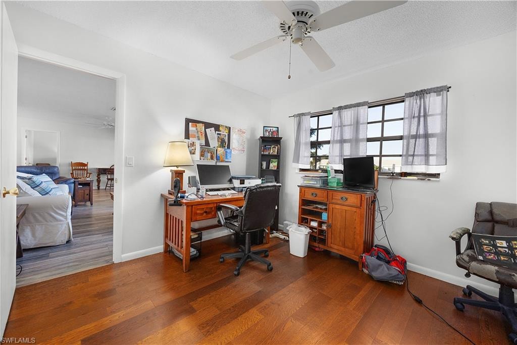Office area with ceiling fan, dark wood-style floors, and a textured ceiling