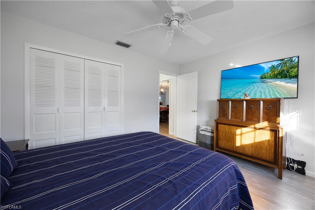 Bedroom featuring a textured ceiling, wood finished floors, a closet, and a ceiling fan