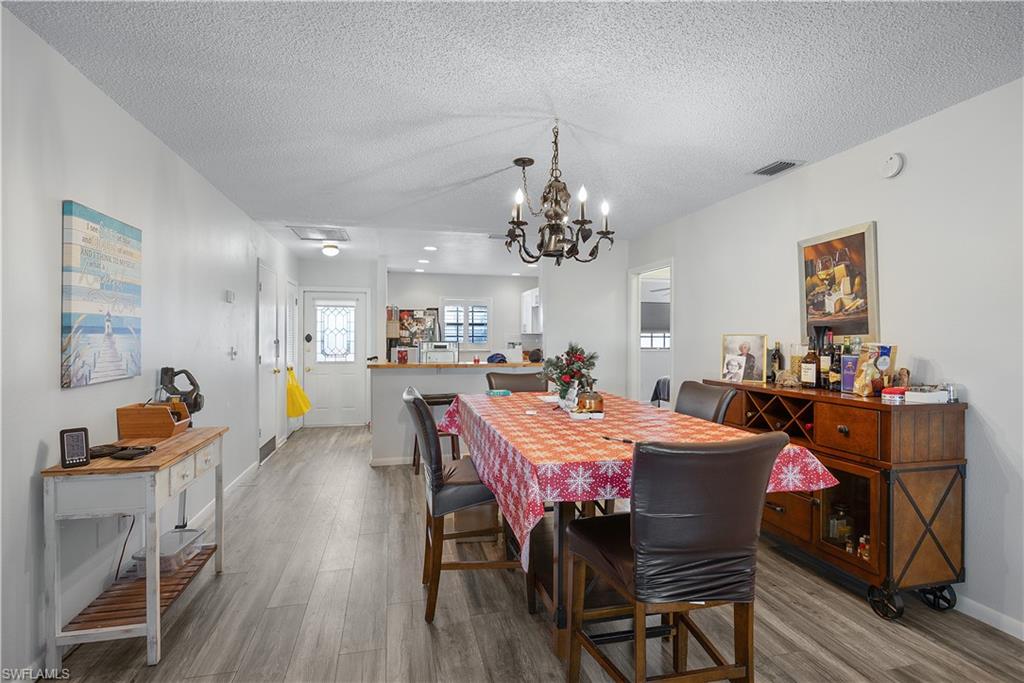 Dining room with a textured ceiling, a chandelier, and wood finished floors