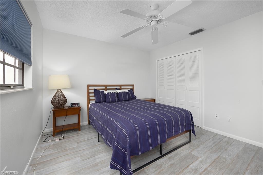 Bedroom with wood finished floors, a ceiling fan, a textured ceiling, and a closet
