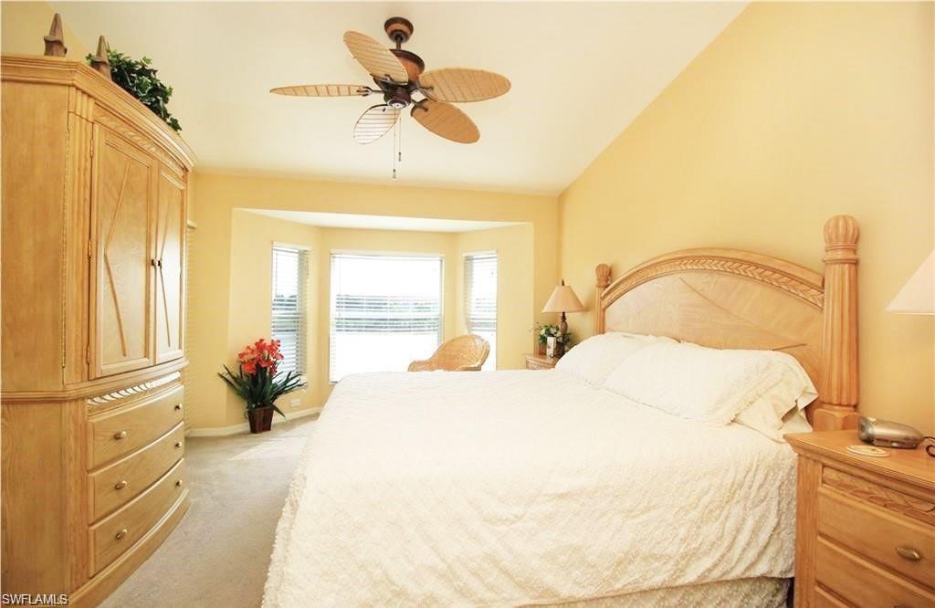 Carpeted bedroom featuring ceiling fan and vaulted ceiling