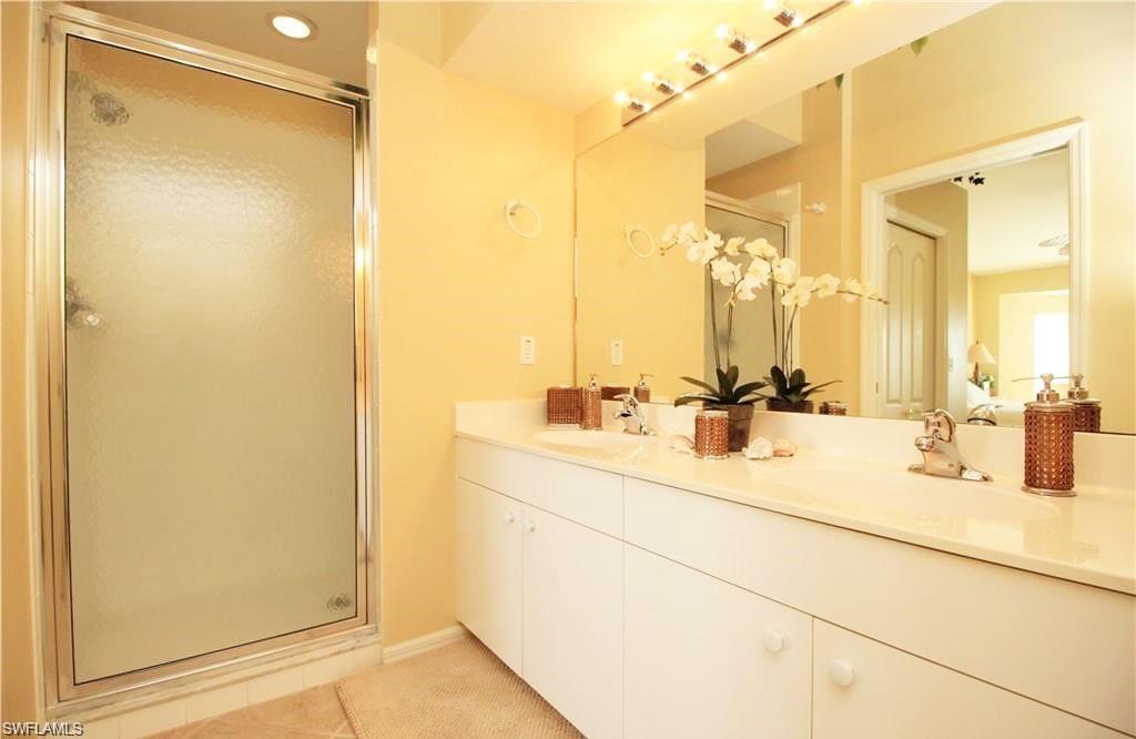 Bathroom featuring tile patterned floors, a shower with door, and vanity