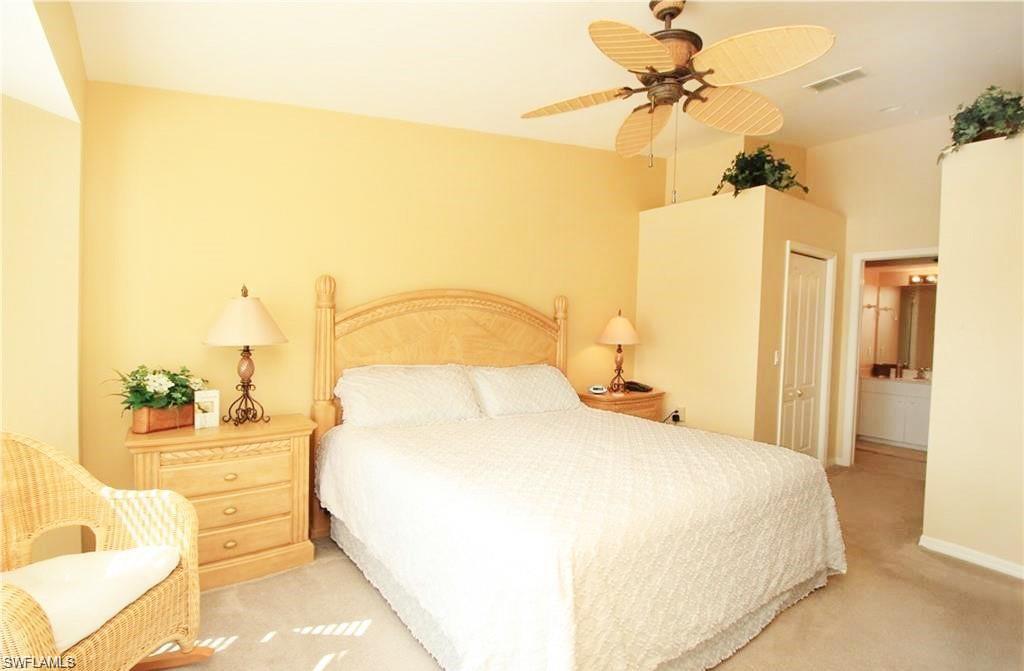 Bedroom with light carpet, a closet, ensuite bathroom, and ceiling fan