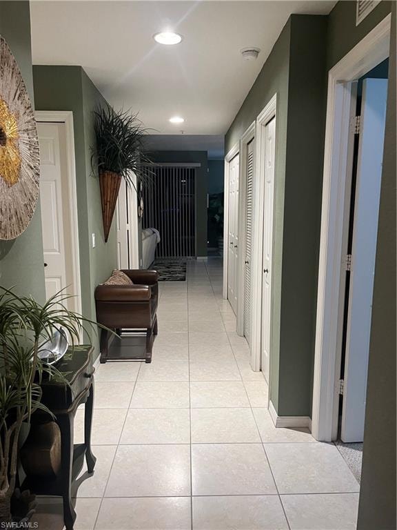 Hallway featuring tile flooring, recessed ceiling lighting, and multiple louvered bifold doors