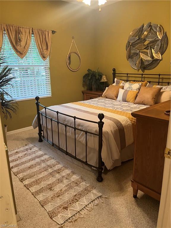 Guest bedroom featuring window with horizontal blinds and valances, and a ceiling-mounted fan with integrated lighting