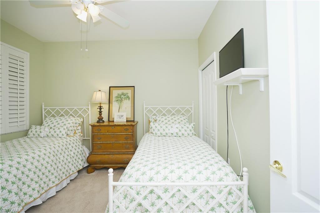 Carpeted bedroom with ceiling fan and a closet