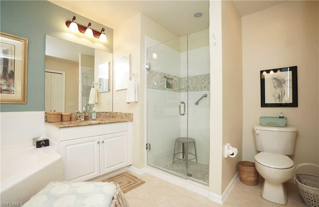 Full bathroom with tile patterned floors, vanity, toilet, and shower with separate bathtub