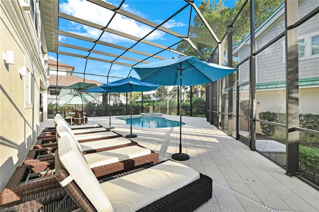 View of swimming pool featuring glass enclosure, an in ground hot tub, and a patio area