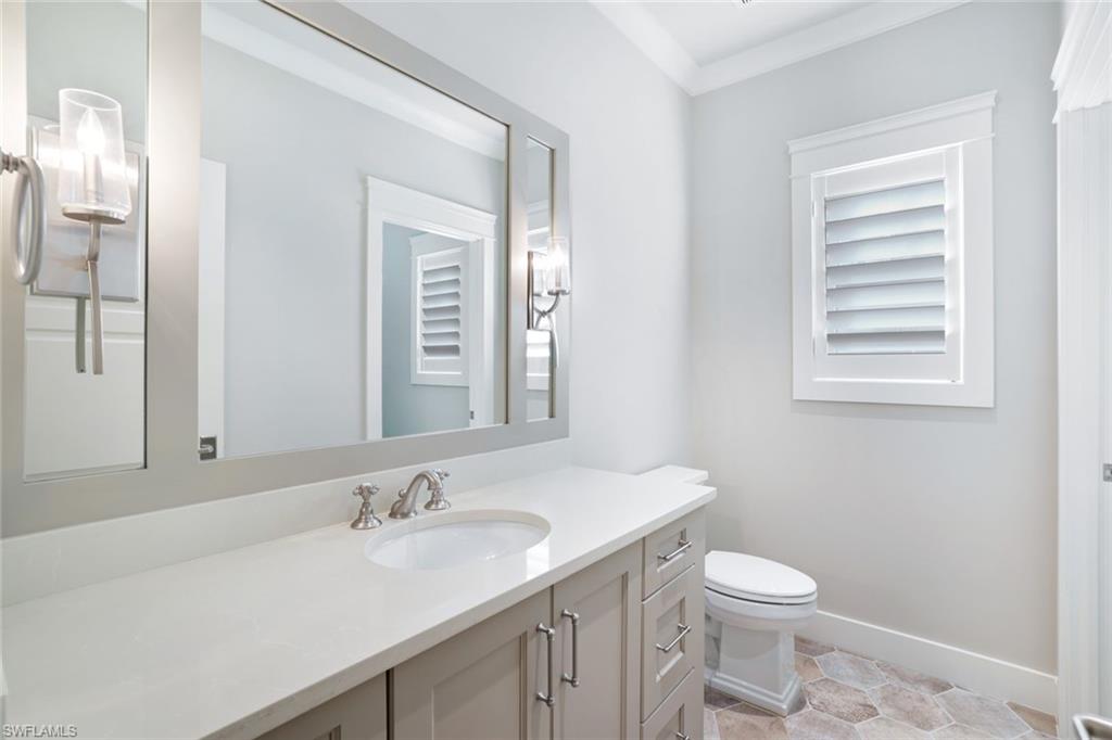 Bathroom with ornamental molding, toilet, vanity, and tile patterned floors