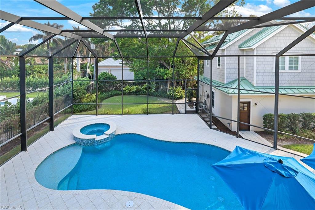 View of swimming pool with glass enclosure, a yard, a patio, and an in ground hot tub