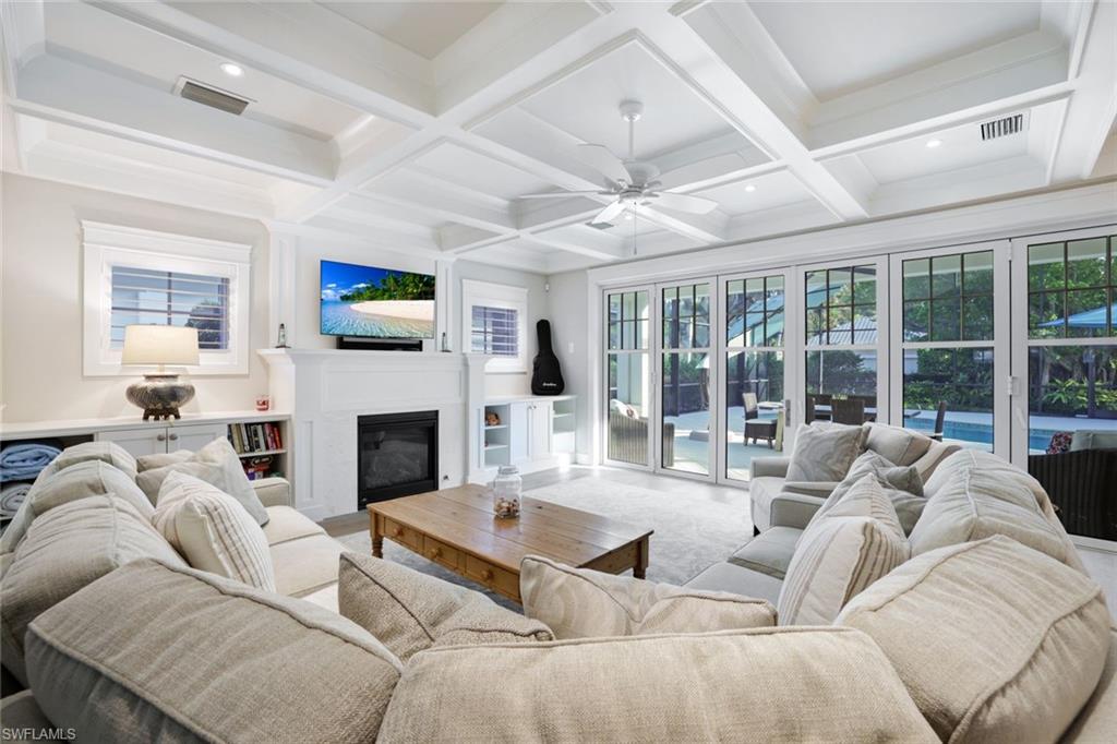 Living room featuring beamed ceiling, coffered ceiling, and ceiling fan