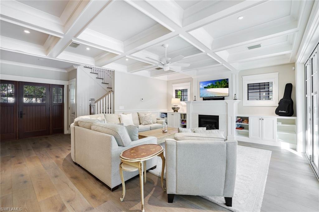 Living room featuring ceiling fan, beam ceiling, light wood-type flooring, and coffered ceiling