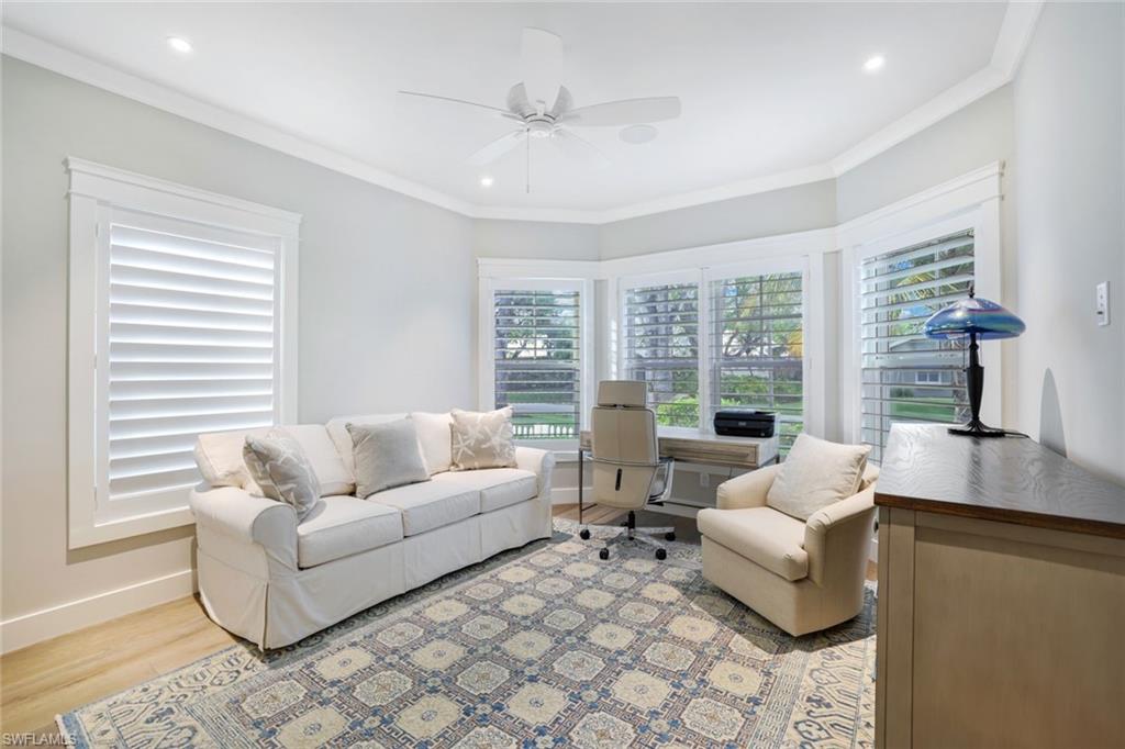 Living room with ornamental molding, light wood-type flooring, and ceiling fan