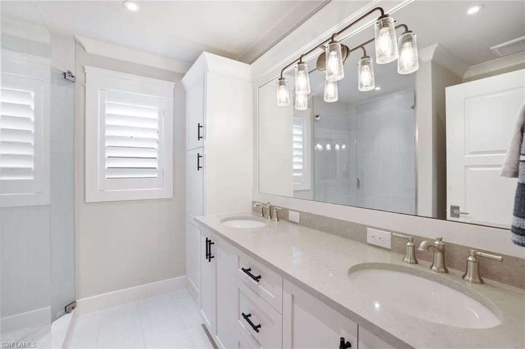 Bathroom with a shower with door, vanity, tile patterned flooring, and crown molding