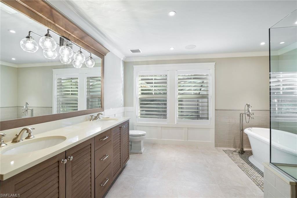 Bathroom with ornamental molding, vanity, a tub, tile patterned flooring, and toilet