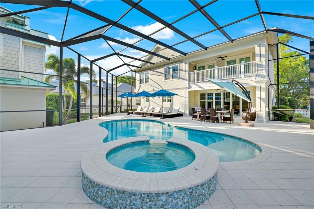 View of pool with glass enclosure, ceiling fan, an in ground hot tub, and a patio area