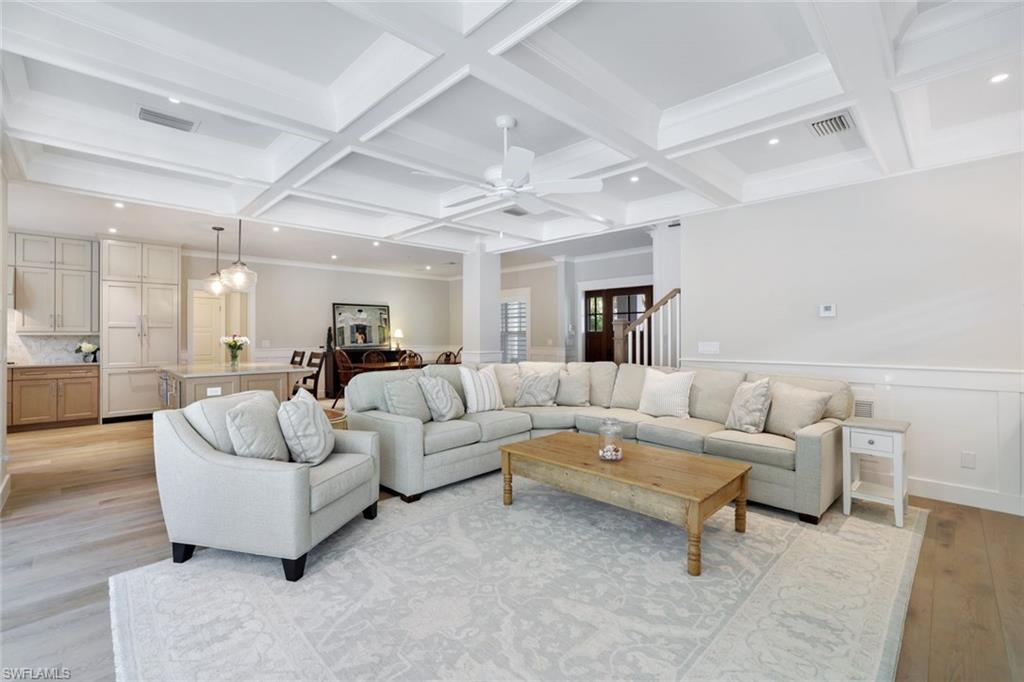 Living room with beam ceiling, coffered ceiling, ceiling fan, and light hardwood / wood-style flooring
