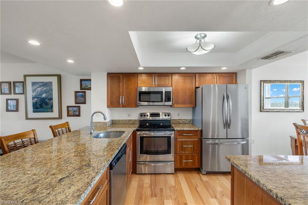Kitchen featuring wood-finish flooring, granite countertops, and stainless steel appliances