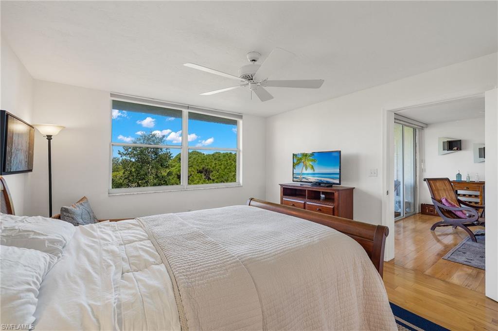 Bright room featuring a large window, a ceiling fan, and light wood-finish flooring