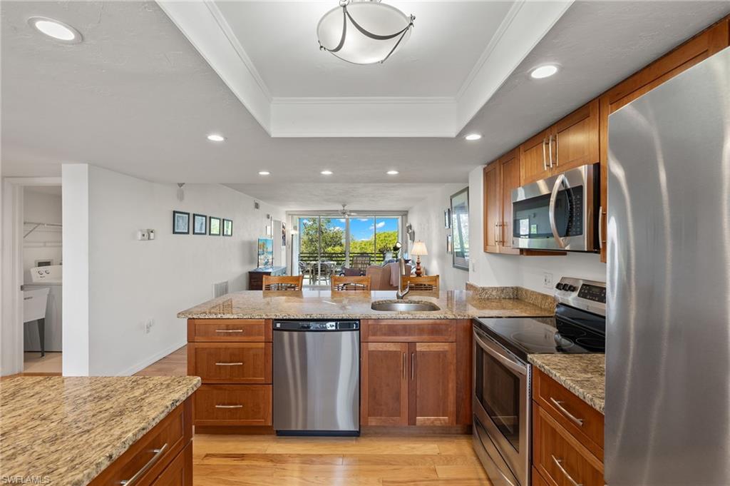 Open-concept kitchen featuring wood-finish cabinetry, stainless steel appliances, and light-toned countertops