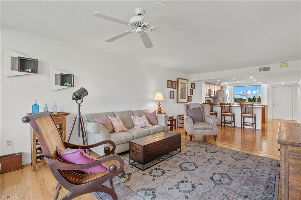 Open-concept living space featuring wood-finish flooring, white walls, and a ceiling fan