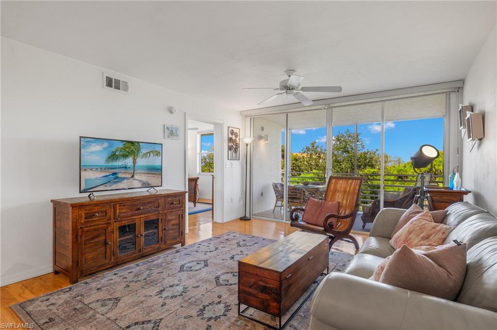 Living area featuring wood-finish flooring, a ceiling fan, and large sliding glass doors opening to an outdoor balcony