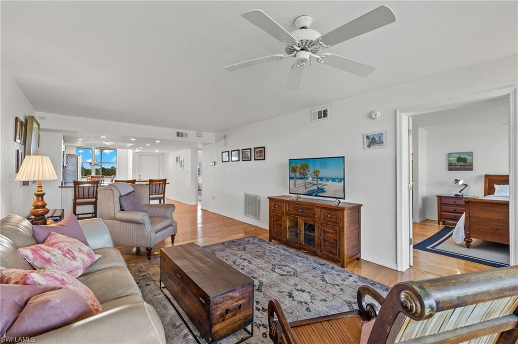 Living area featuring wood-finish flooring, a ceiling fan, and white walls