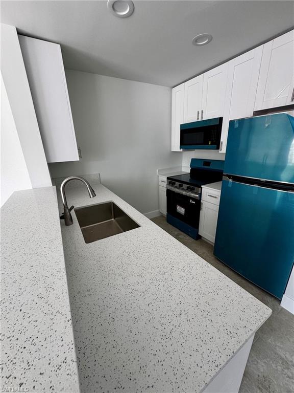 Contemporary kitchen featuring speckled countertops, white shaker cabinetry, stainless steel sink with gooseneck faucet, and integrated overhead lighting