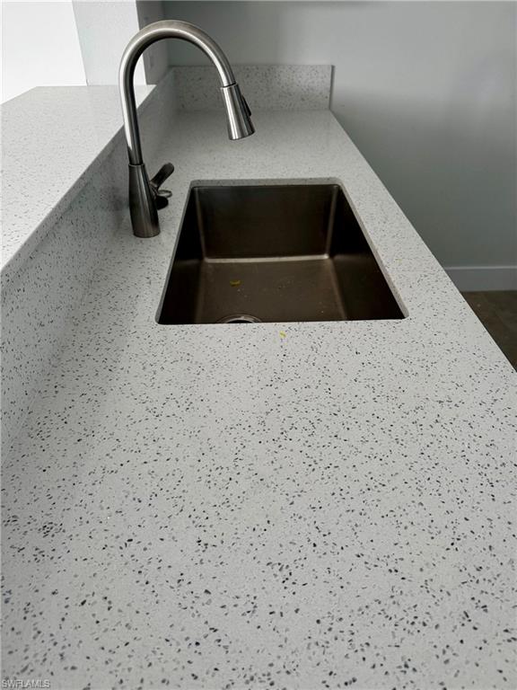 White speckled countertop with an undermount stainless steel sink and a gooseneck faucet