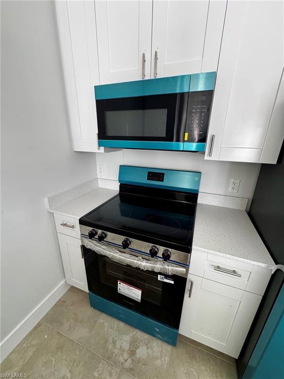 Modern kitchen featuring new, stainless steel appliances including an electric range with an oven and an over-the-range microwave