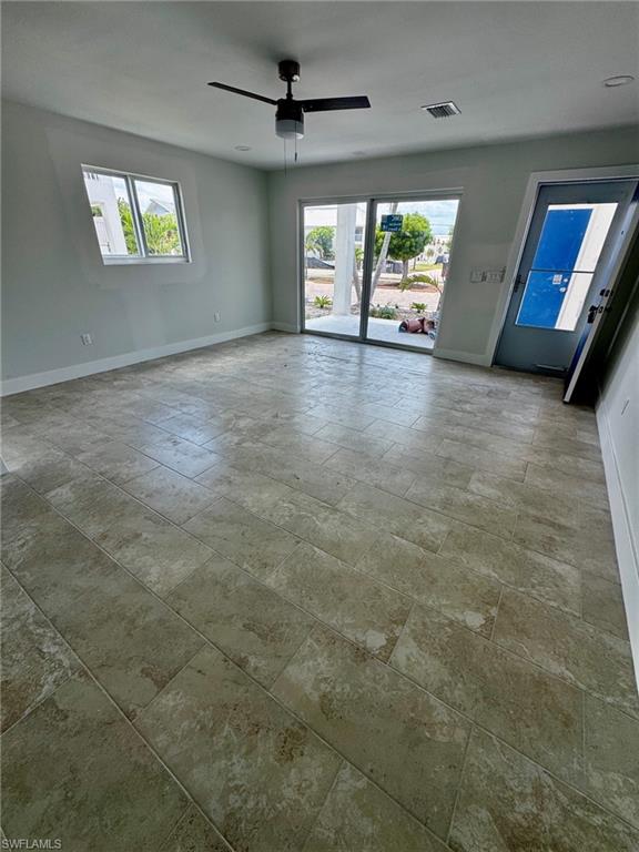Spacious room featuring large format tile flooring, a modern ceiling fan, recessed lighting, and a sliding glass door providing exterior access