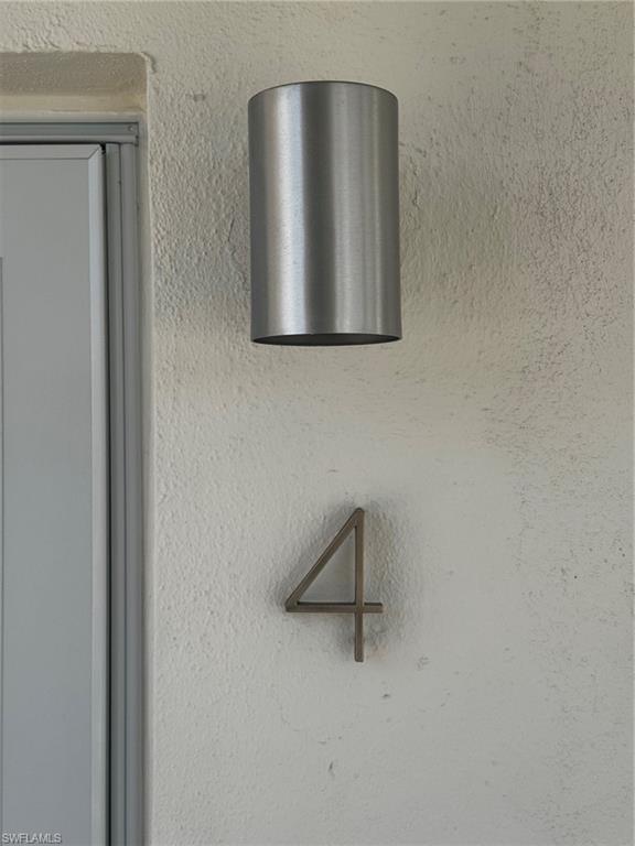Modern brushed metal cylindrical outdoor light fixture mounted on textured exterior wall