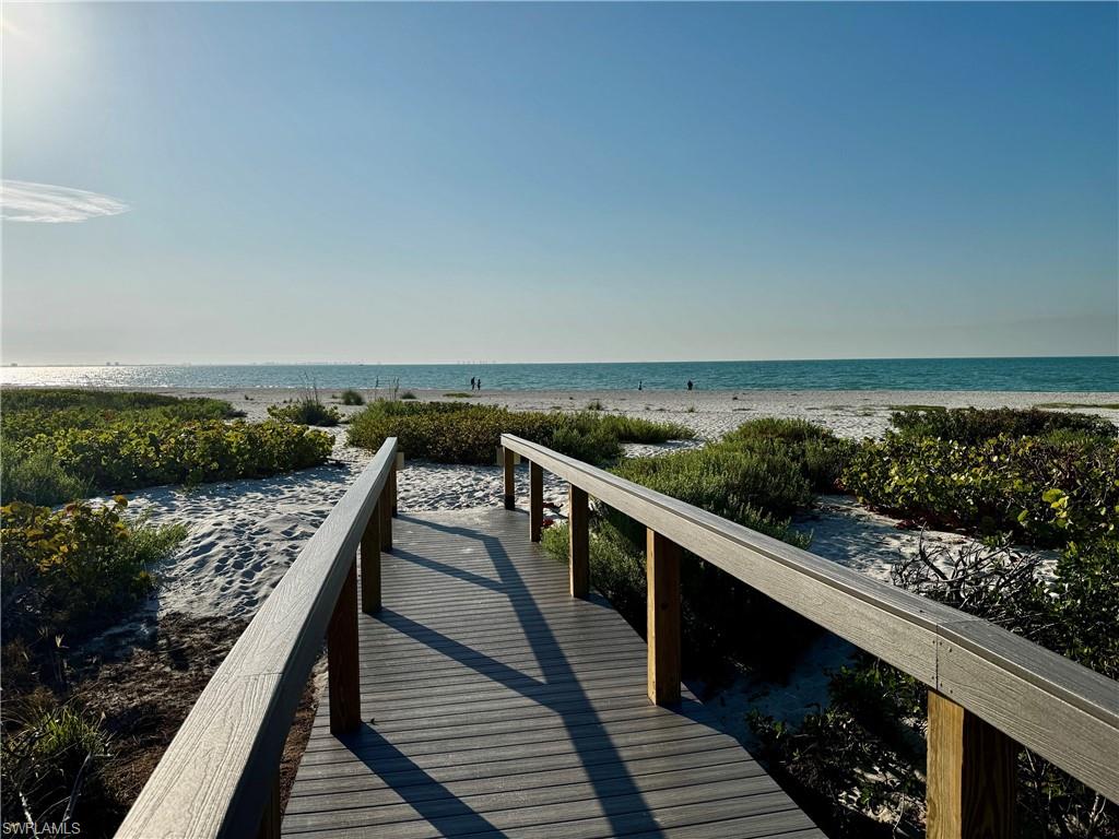 Boardwalk entrance to a white sand beach with natural vegetation