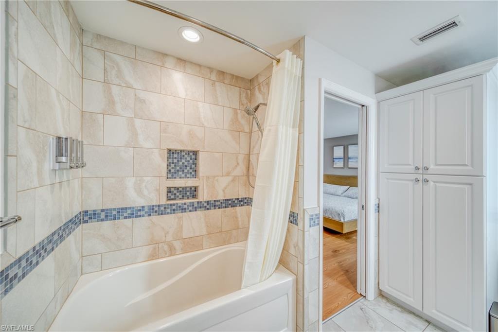 Bathroom featuring connected bathroom, shower / bath combination with curtain, and recessed lighting