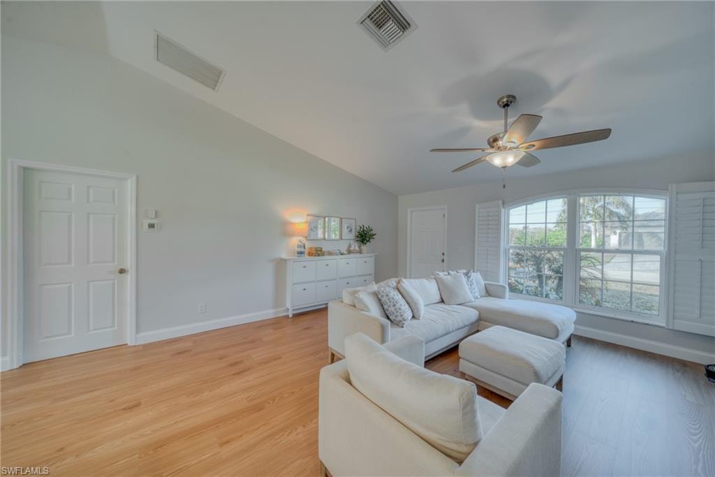 Living area with vaulted ceiling, light wood finished floors, and a ceiling fan
