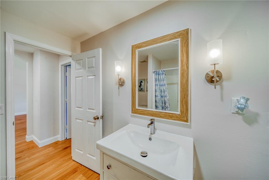 Bathroom featuring a shower with curtain, vanity, and light wood-style flooring