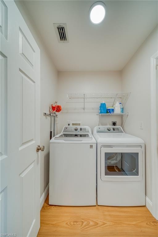 Laundry room featuring light wood-type flooring and washing machine and clothes dryer