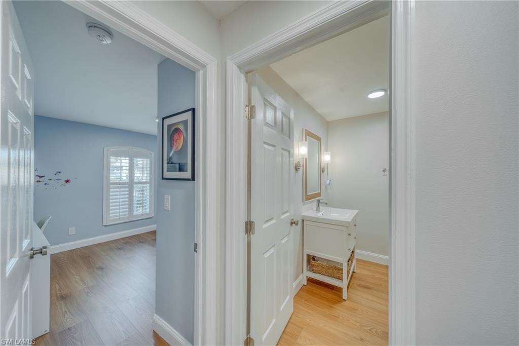 Hallway with light wood-type flooring and baseboards