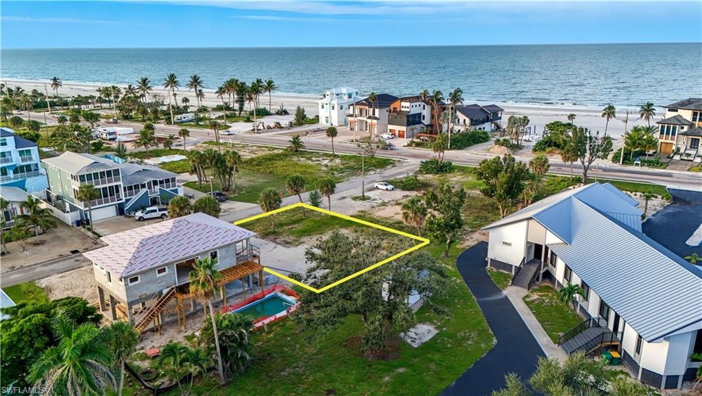 Aerial perspective of suburban area featuring expansive beach and property boundaries highlighted - Virtually Edited Image