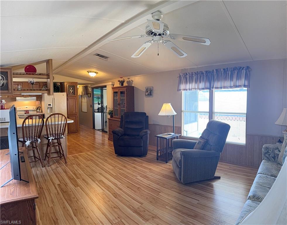 Open-concept living space featuring wood-look flooring,  ceiling fan, and abundant natural light from multiple windows.