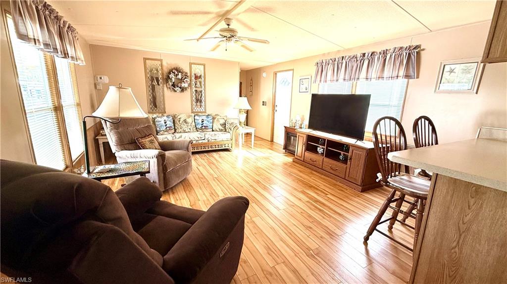 Living area is light filled with wood-look flooring, a ceiling fan