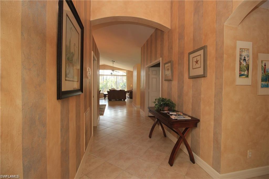 Corridor with lofted ceiling and light tile patterned floors