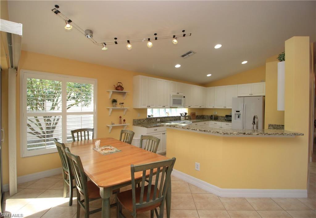 Tiled dining space with sink and vaulted ceiling