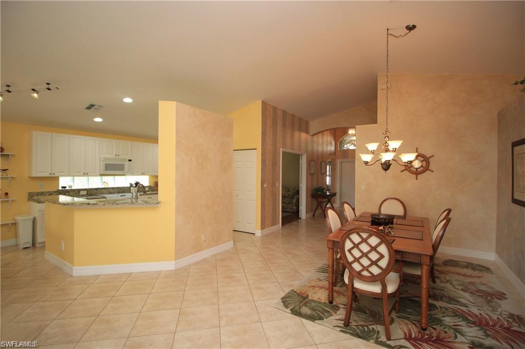 Tiled dining area with lofted ceiling and an inviting chandelier