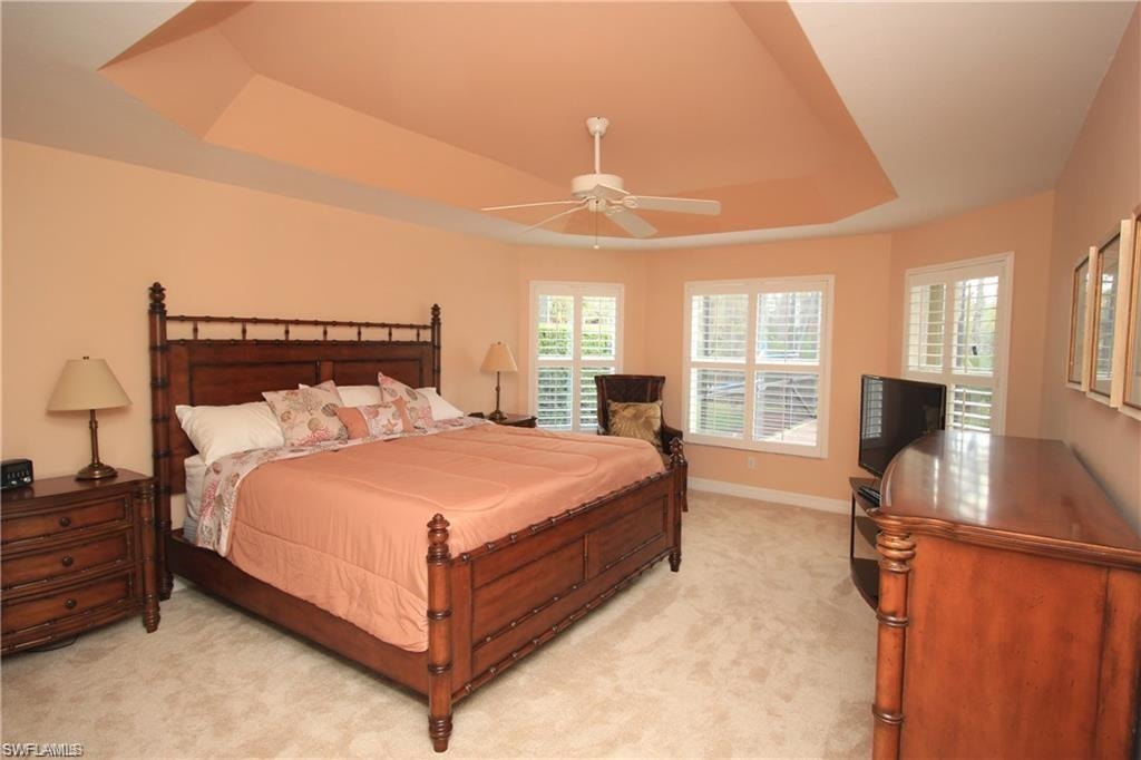 Bedroom featuring ceiling fan, light colored carpet, and a raised ceiling