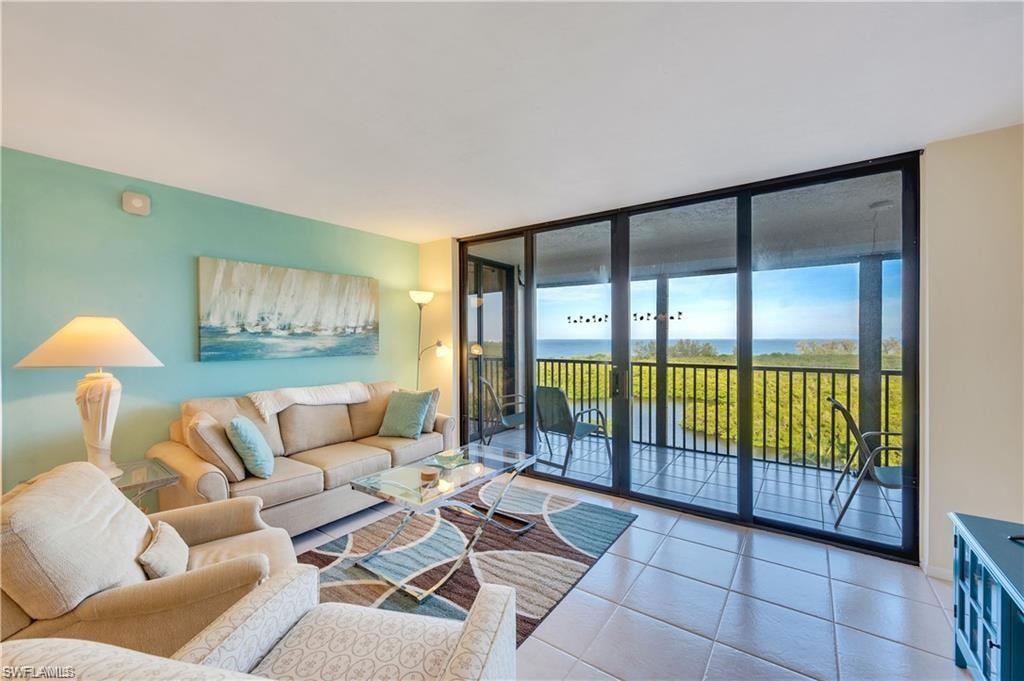 Living room with expansive windows, a water view, and tile patterned flooring