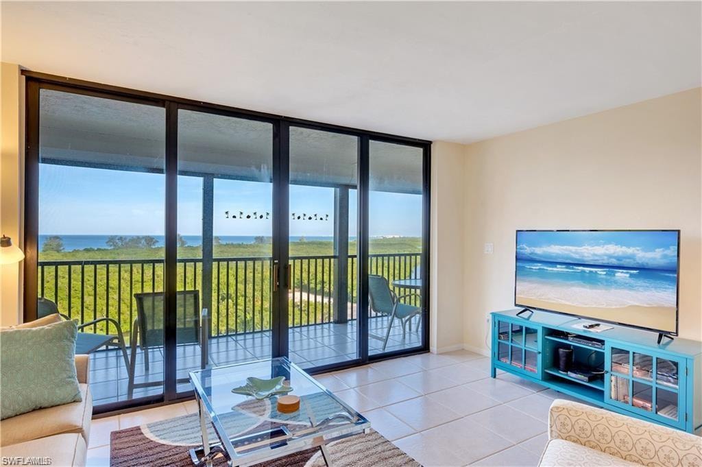 Living room featuring light tile patterned flooring, a water view, and a wealth of natural light
