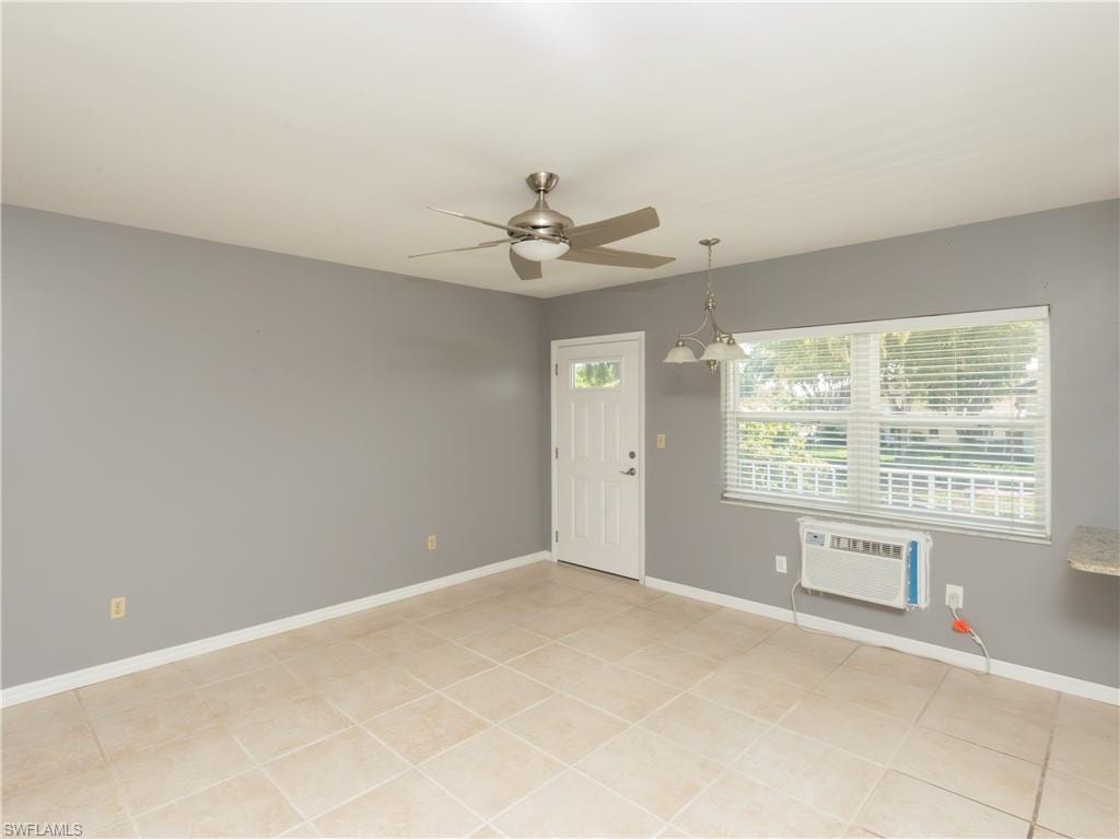 Spacious room featuring tile flooring, neutral wall tones, a ceiling fan with integrated lighting, a white entrance door with decorative glass, and a large window with horizontal blinds