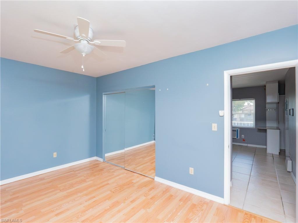 Room featuring wood-finish flooring, a ceiling fan, and mirrored closet doors